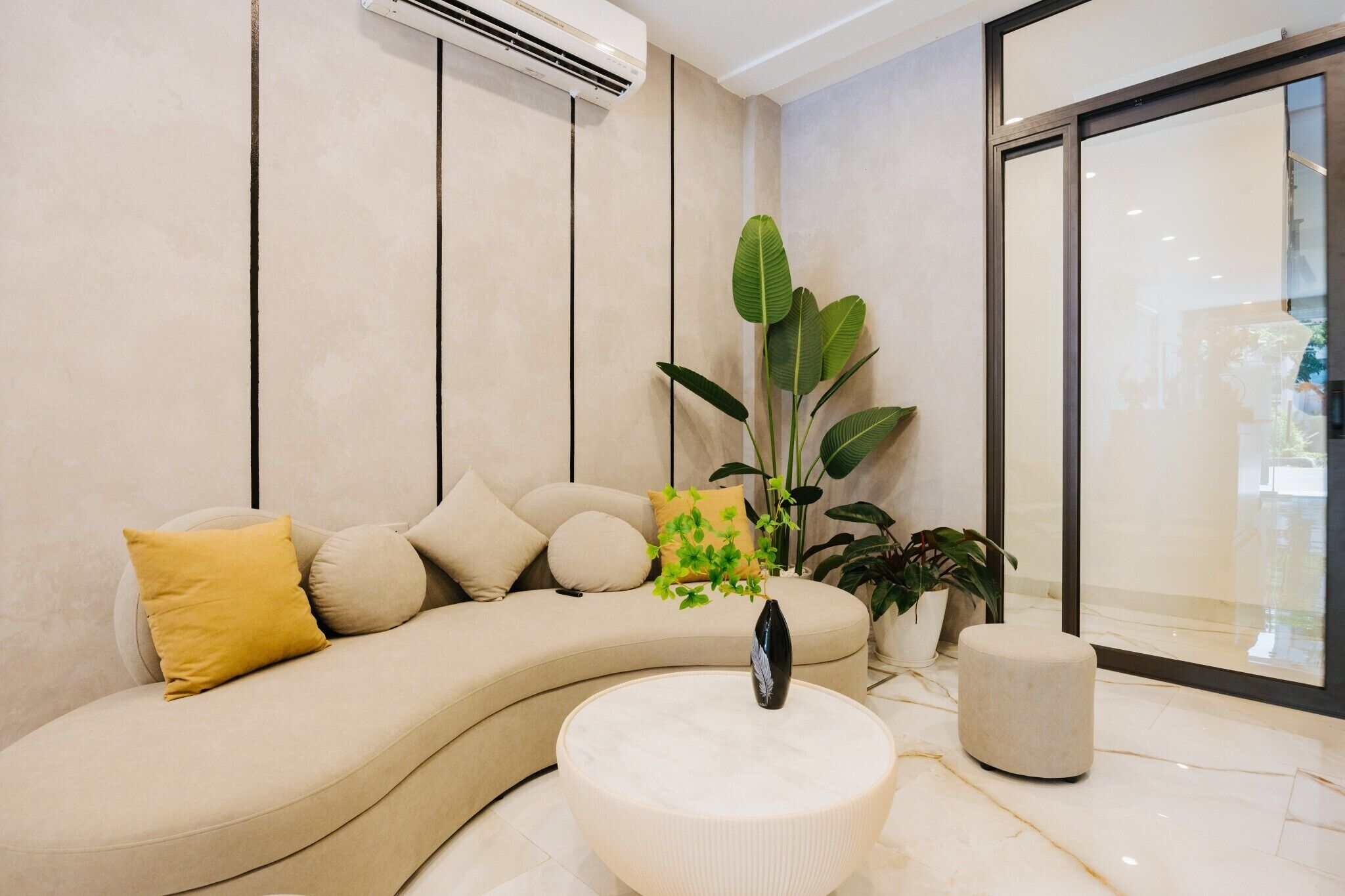 Un salon moderne avec un canapé aux lignes courbes, une table basse ronde et une plante en pot.