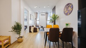 Un salon moderne comprenant un canapé, une table à manger et des chaises, une petite table avec une plante et un grand téléviseur à écran plat.