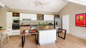 Une cuisine moderne avec des meubles blancs, un îlot central et un ventilateur de plafond.