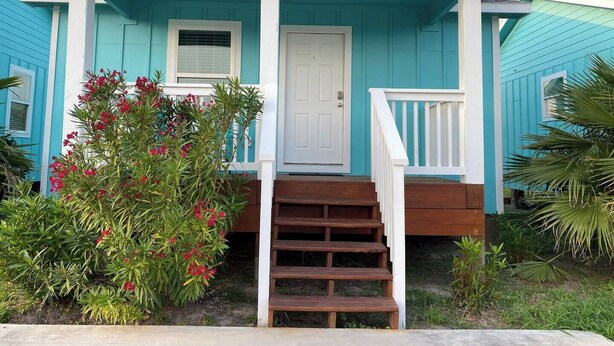 A two-story house with a front porch, a white door, and a staircase leading to the entrance.
