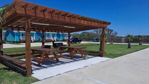 Una pérgola de madera con mesas de picnic en un patio trasero.