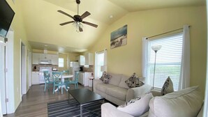 Un espacio habitable compacto con kitchenette, comedor y zona de estar con sofá y mesa de centro.
