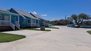 A row of blue houses with white railings and a clear sky.