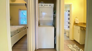 A compact kitchen with a built-in refrigerator and oven, a small countertop, and a window with blinds.