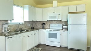 A kitchen with white cabinets, a microwave, a stove, and a refrigerator.