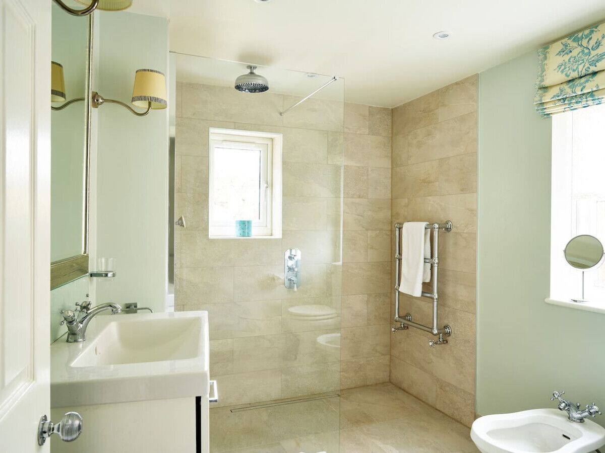 A bathroom with a glass-enclosed shower, a sink, and a mirror.