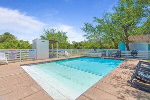A swimming pool with a lifeguard station, pool rules sign, and a covered area.