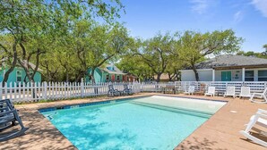 A swimming pool with a white fence, lounge chairs, and a wooden deck. - This cottage is a 2 bedroom(s), 2 bathrooms, located in Rockport, TX. (Rockport)