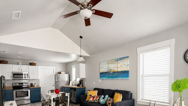 A spacious living area with a kitchen, dining table, sofa, and a ceiling fan. - This cottage is a 2 bedroom(s), 2 bathrooms, located in Rockport, TX. (Rockport)