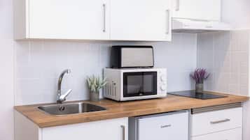 Een keuken met een spoelbak, een magnetron, een broodrooster en een kast.