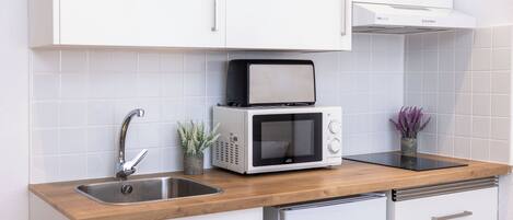Une cuisine équipée d’un évier, d’un four à micro-ondes, d’un grille-pain et d’un placard.