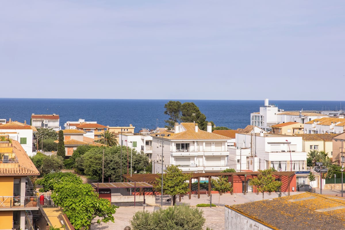 A coastal town with buildings, a clear sky, and the sea in the background.
