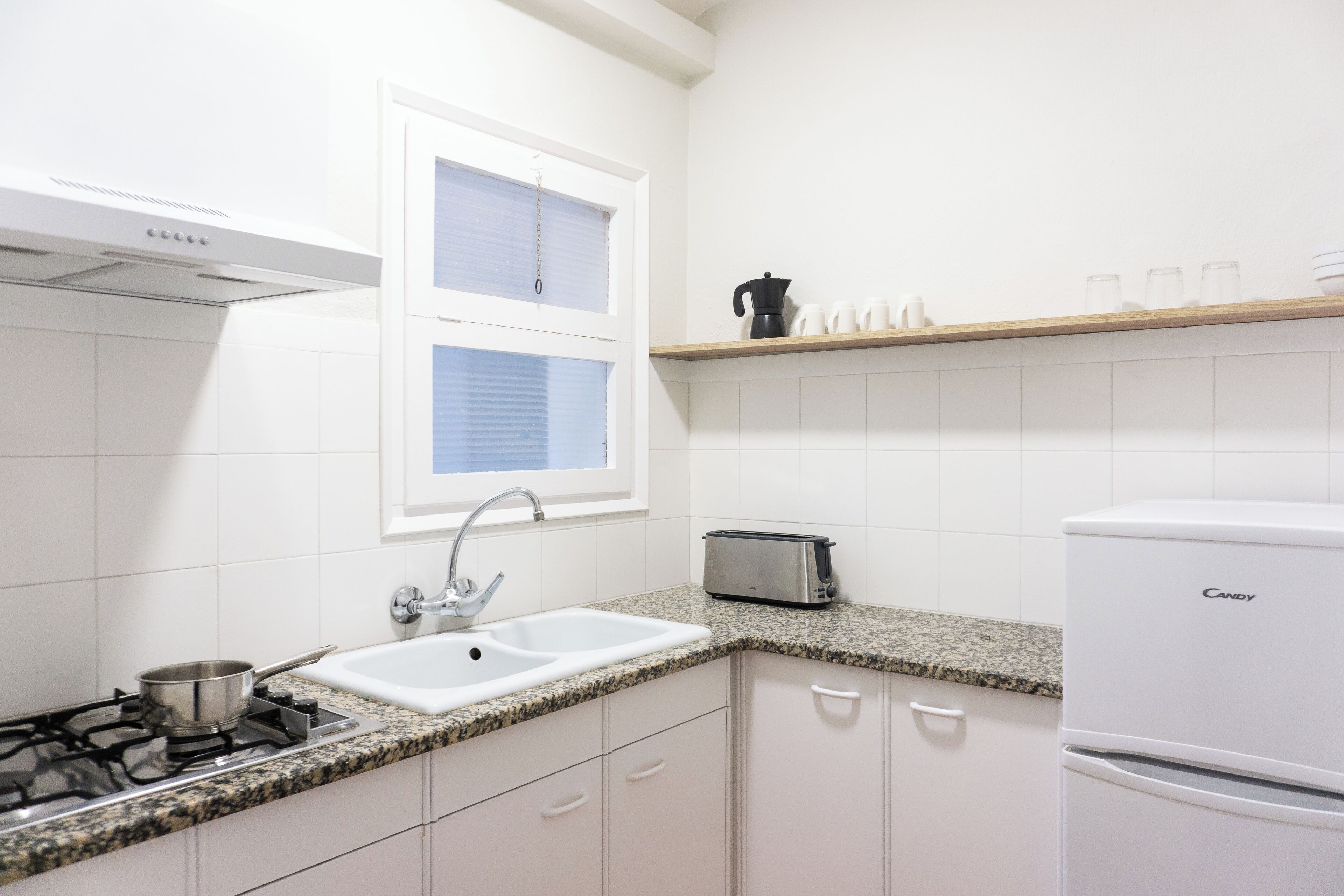 A kitchen with white cabinets, a granite countertop, a stove, a sink, a toaster, and a refrigerator.