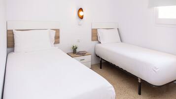 A twin room with two beds, a nightstand, a wall-mounted light, and a window.