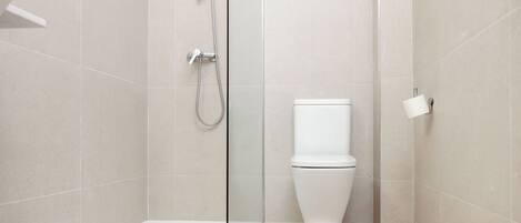 A modern bathroom with a glass shower enclosure, a white toilet, and a tiled floor.