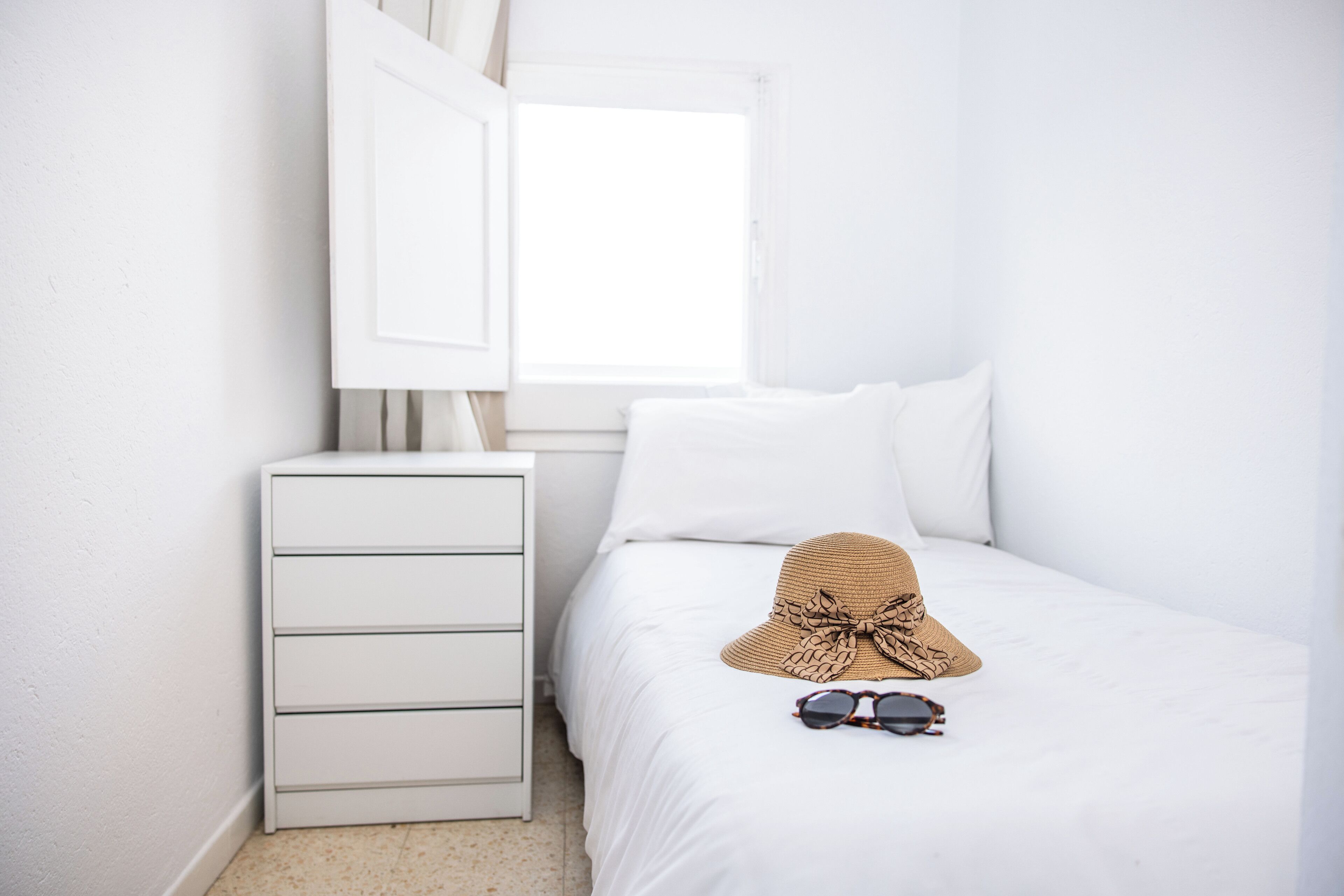 A bedroom with a bed, a nightstand, and a window.