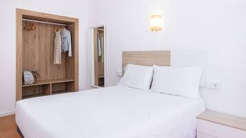 Une chambre à coucher avec une armoire en bois, un lit avec une literie blanche et une table de chevet.