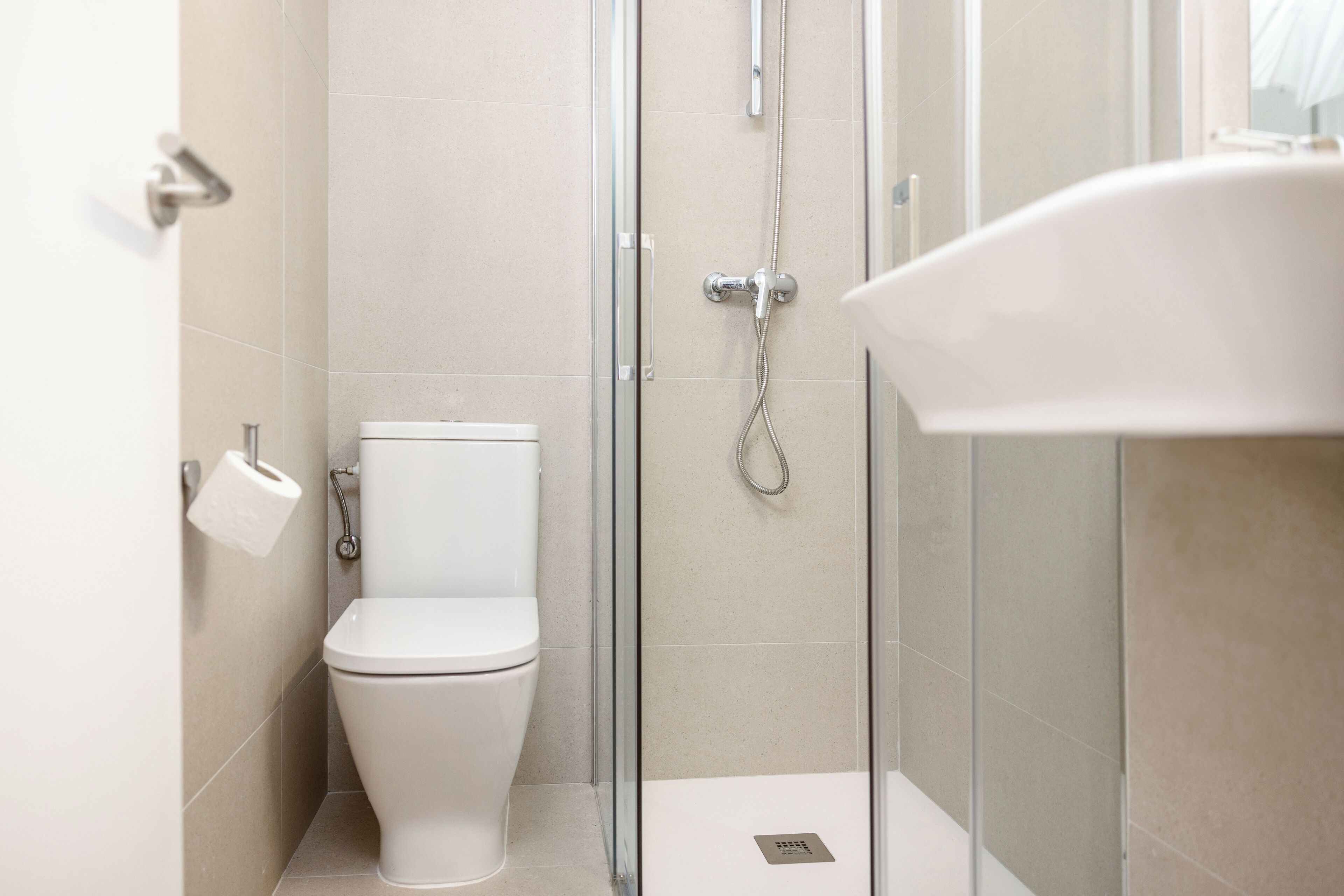 Ein modernes Badezimmer mit Toilette, einer gläsernen Dusche und einem weißen Waschbecken.