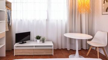 Ein modernes Zimmer mit einem weißen TV-Schrank, einem kleinen Topfpflanzen, einem runden Tisch und einem weißen Stuhl.