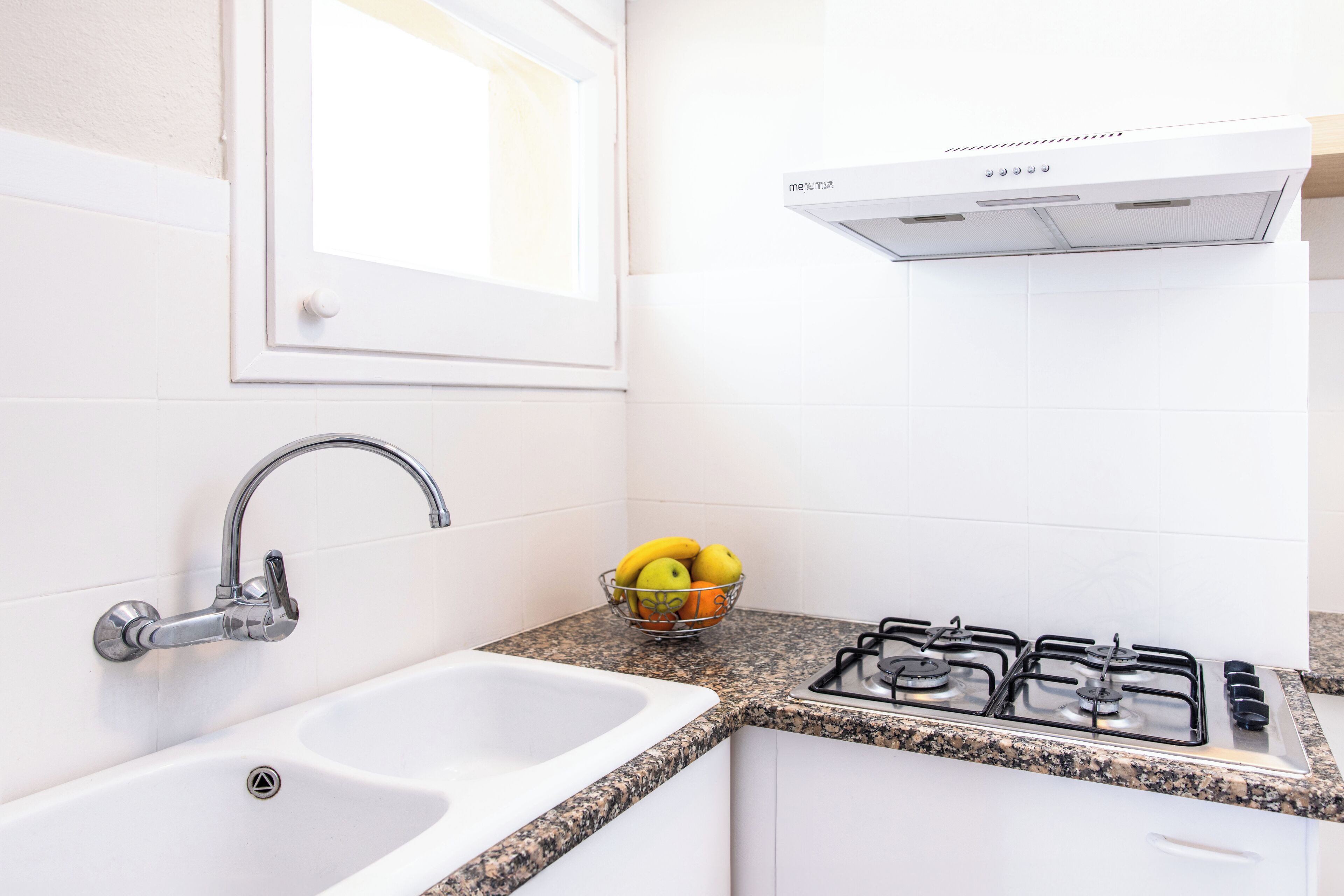 A kitchen with a double sink, a gas stove, and a window above the sink.