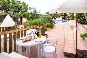 Un patio con una mesa redonda, sillas blancas y una valla de madera.