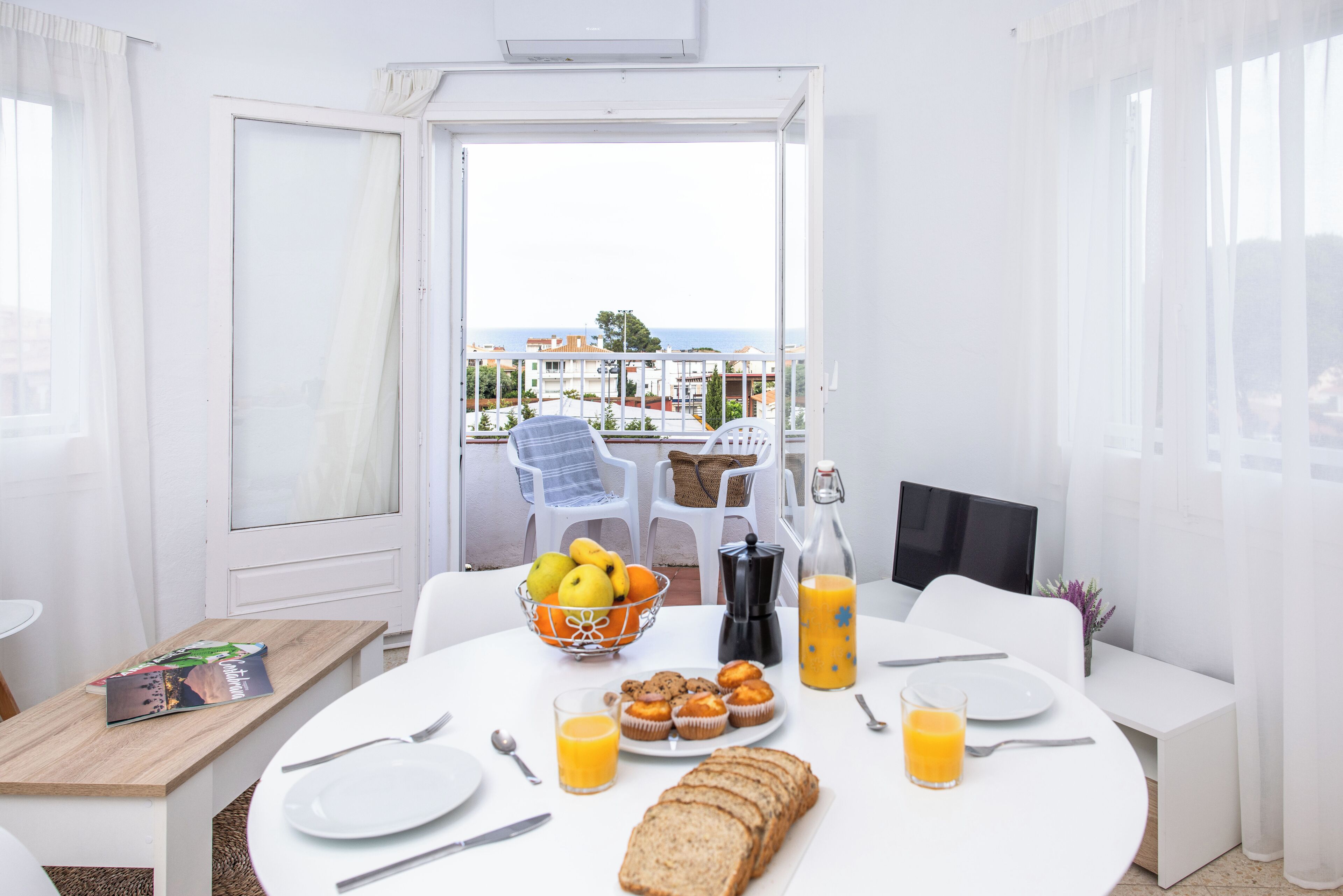 Desayuno con una mesa, alimentos para el desayuno y vista al mar.