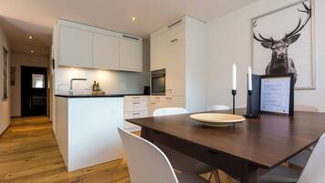 Una cocina moderna con armarios blancos, una mesa de comedor de madera y una obra de arte con un ciervo enmarcado.