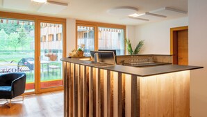 Una cocina moderna con una isla de madera, ventanas amplias y vista a un edificio.