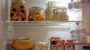 Ein Kühlschrank mit Regalen, auf denen verschiedene Lebensmittel stehen, darunter Einmachgläser, ein Käselaib und verpackter Käse.