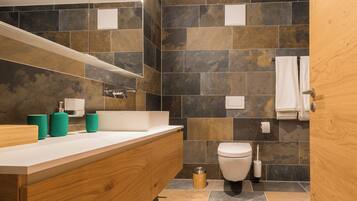 Un baño moderno con tocador de madera, un lavabo blanco y un espejo grande.