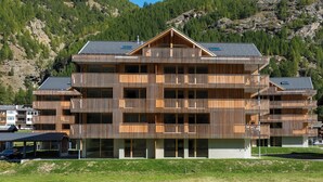 Un edificio de madera de varios pisos con balcones, frente a un paisaje montañoso.