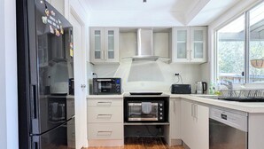 Een moderne keuken met een zwarte koelkast, een inbouwoven, een magnetron en een vaatwasser.
