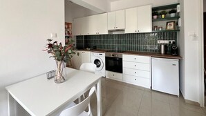 A compact kitchen with white cabinets, a washing machine, and a coffee maker. - Cosy 1/bdr central apart near the beach

 (Paphos)