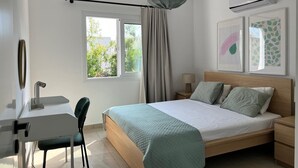A modern bedroom with a bed, bedside tables, a desk, and a chair. - Cosy 1/bdr central apart near the beach

 (Paphos)