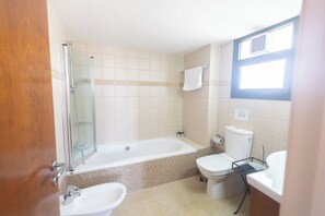 Ein Badezimmer mit Duschkabine, Badewanne, Toilette und Waschbecken.