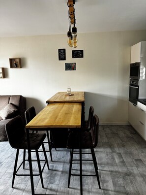 Une cuisine moderne avec une table et des chaises en bois, un four encastré et un réfrigérateur.