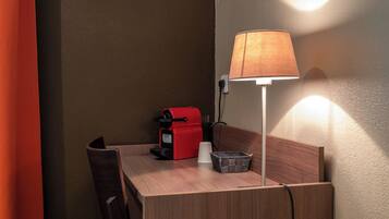 A small wooden table with a red coffee maker, a white cup, and a basket.