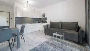 Ein modernes Wohnzimmer mit Küche, Essbereich und einem grauen Sofa.