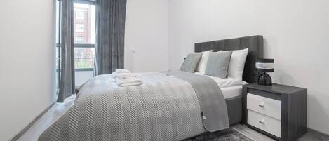 Una camera da letto moderna con un letto, un comodino e una finestra con tende.