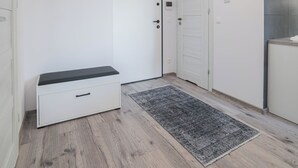 Ein moderner, minimalistischer Flur mit einer Bank, einem Teppich und einer Deckenleuchte.