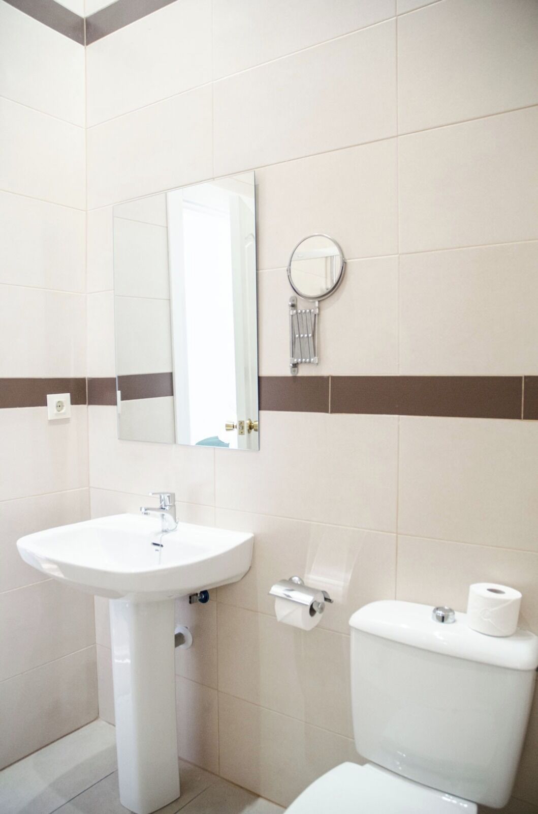 Un baño con un lavabo blanco, un inodoro y un espejo con toallero.