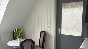Zona pranzo con tavolo rotondo, due sedie, una pianta in vaso e un tappetino d'ingresso con la scritta “WELCOME HOME”.