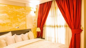 Ein Hotelzimmer mit einem Bett, roten Vorhängen und einer Lampe.