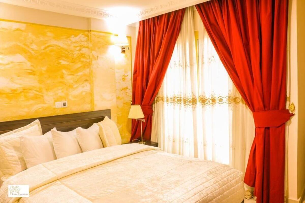 Une chambre d’hôtel avec un lit, des rideaux rouges et une lampe.