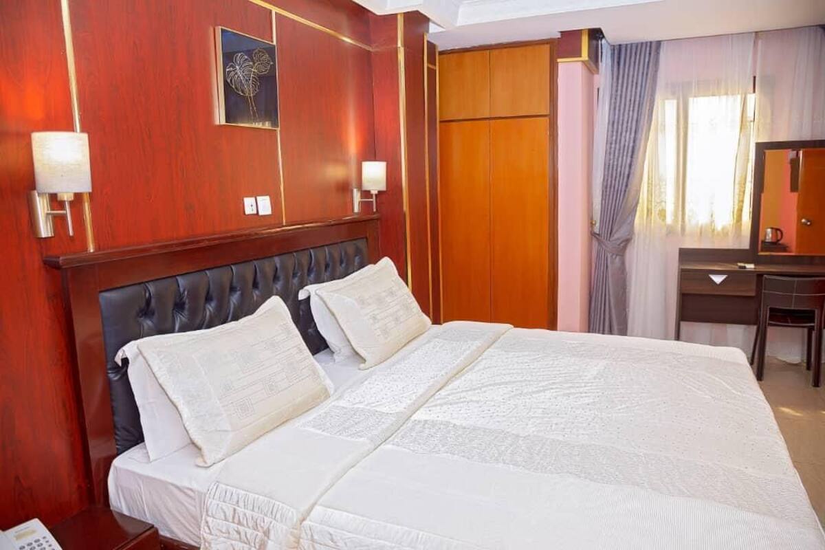 Une chambre d’hôtel avec un grand lit, des boiseries, un bureau et un miroir.