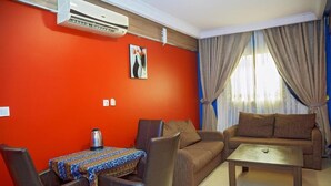 Ein Wohnzimmer mit roter Wand, einer Couch, einem Couchtisch und einem Tisch mit gemustertem Tischläufer.