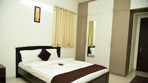Quarto de hotel com cama, guarda-roupa, espelho e porta.