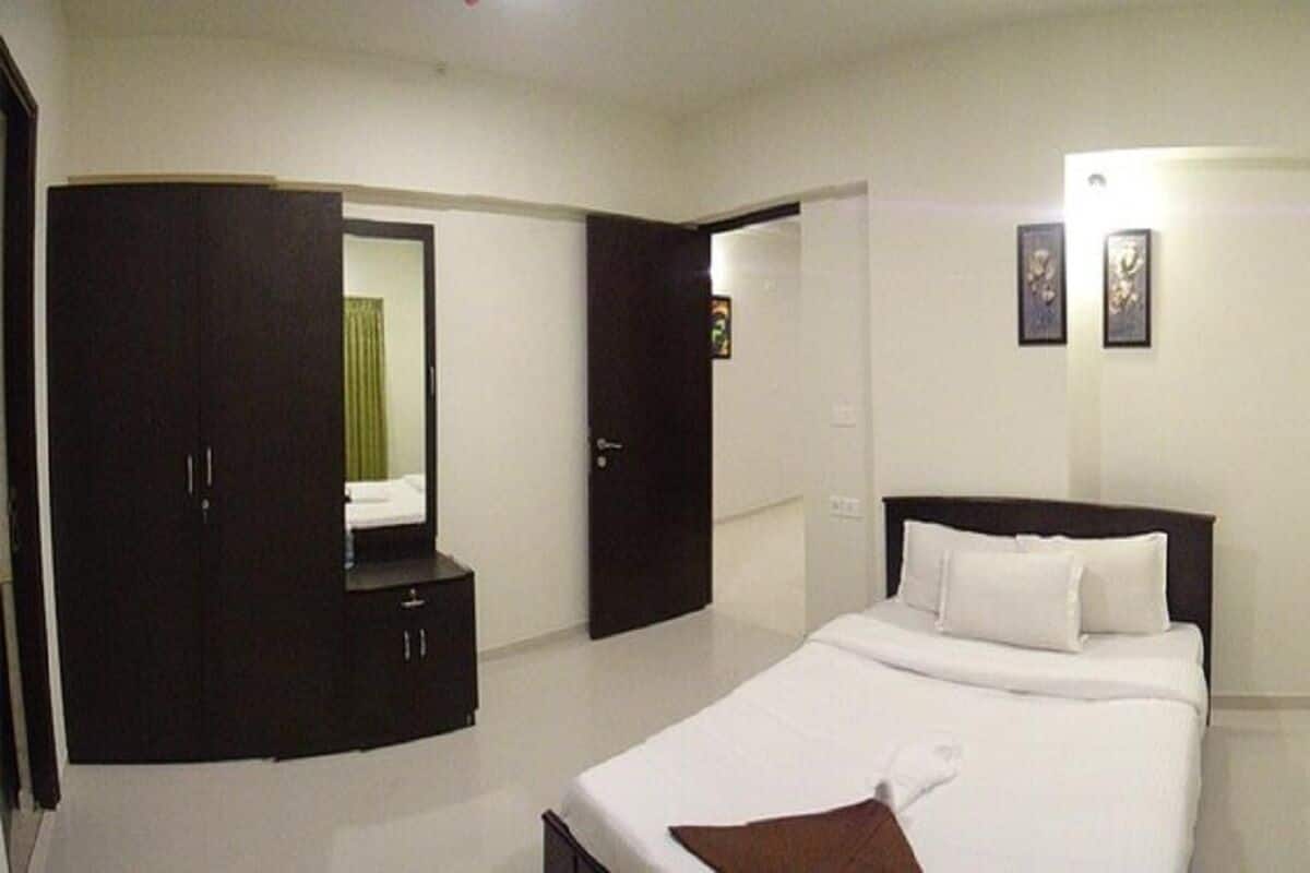A bedroom with a bed, a wardrobe, and a door leading to another room.