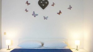 A bedroom with a bed, two bedside tables, and wall decorations including a heart and butterflies. - Cleo Girasole (Porto Recanati)