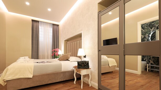 A modern hotel room with a large bed, bedside table, and a mirror. - Vatican Cozy Suites (Rome)